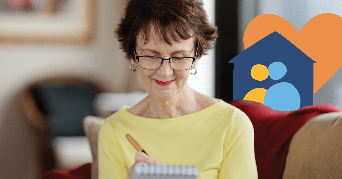 Elderly woman with glasses writing in a notebook, smiling, with a house and heart symbol in the background.