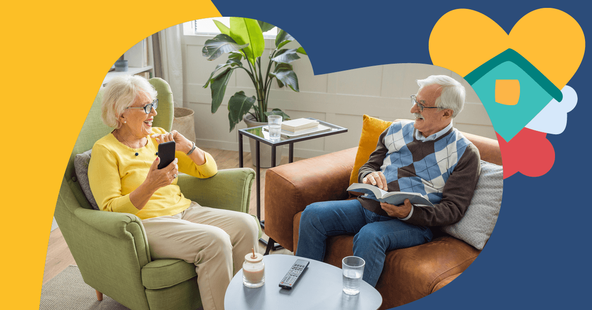 Elderly couple sitting in a cozy living room; woman on phone, man reading a book. Bright decor with a plant and heart-shaped graphics.