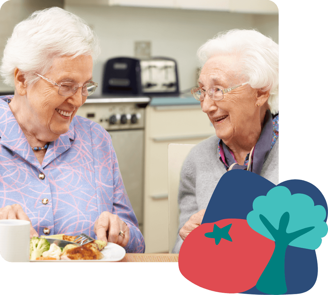 Two elderly women smiling and eating together in a kitchen, with house and tree icons displayed on the side
