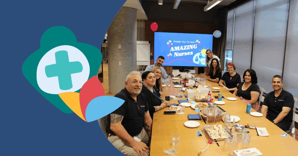 A group of people sitting around a conference table with a screen displaying "Amazing Nurses" in the background.