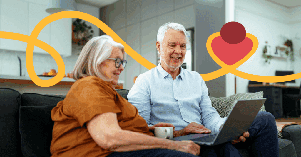 Elderly couple sitting on a couch, using a laptop, smiling. Bright, abstract yellow and red shapes in the background. Cozy living room setting.