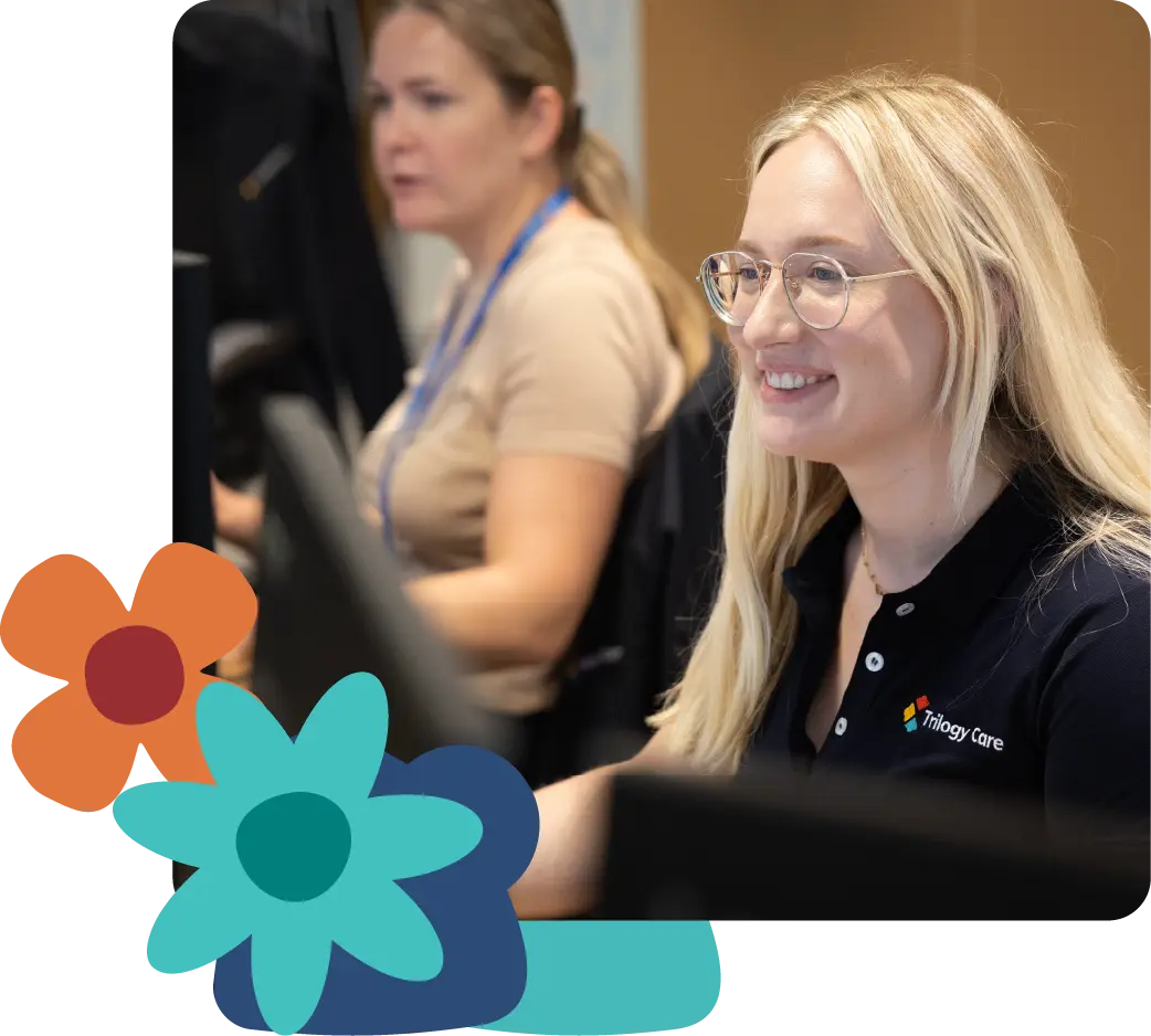 Trilogy Care support worker smiling in the office, with flower icons on the side