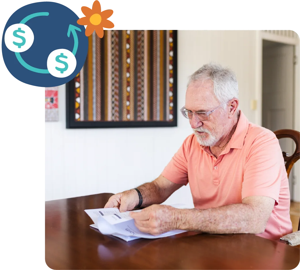 An older man reading through paperwork at his dining table