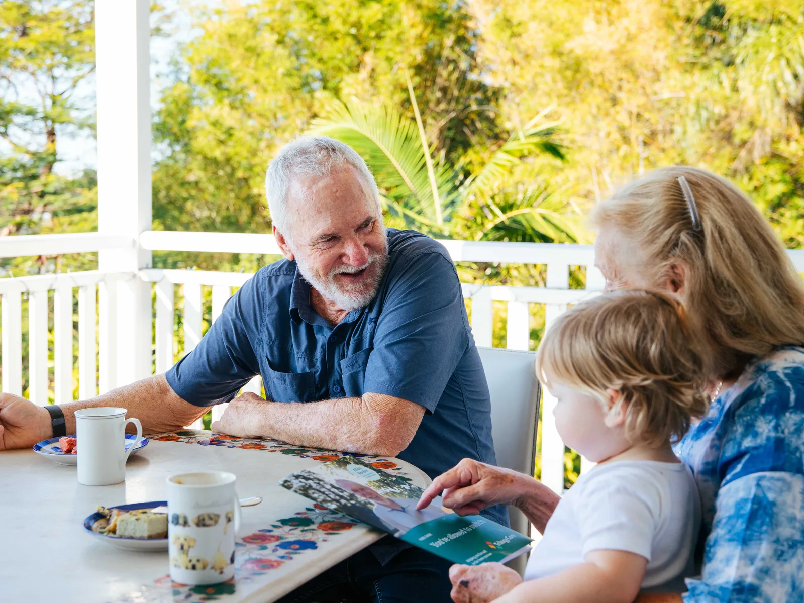 Allan Border at a table with his family, holding the Trilogy Care switching guide