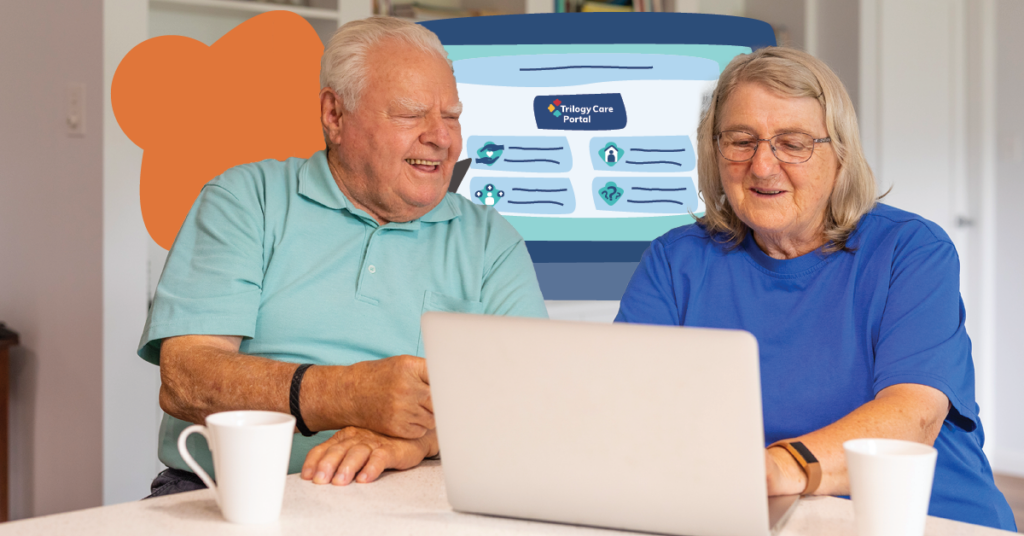 An elderly man and woman are sitting at a kitchen table, smiling while looking at a laptop. They are engaged with the Trilogy Care Portal displayed on the screen. Two coffee mugs are on the table, creating a cozy and engaging atmosphere.