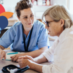 Healthcare professional consulting with an elderly woman at home, symbolising care and support, with a multicolored heart symbol overlaying the image.